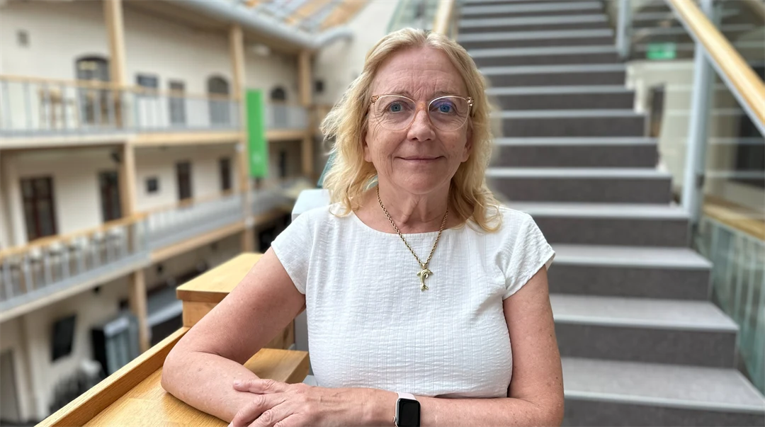 Porträttfoto av en blond kvinna ståendes framför en trappa