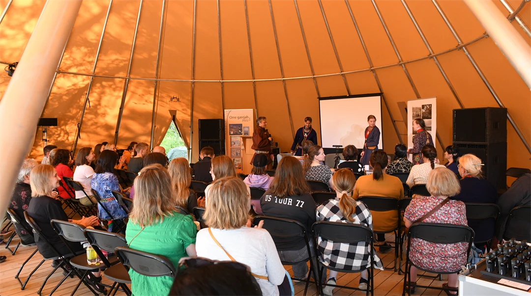 Publik lyssnar på ett panelsamtal i en stor tältkåta.