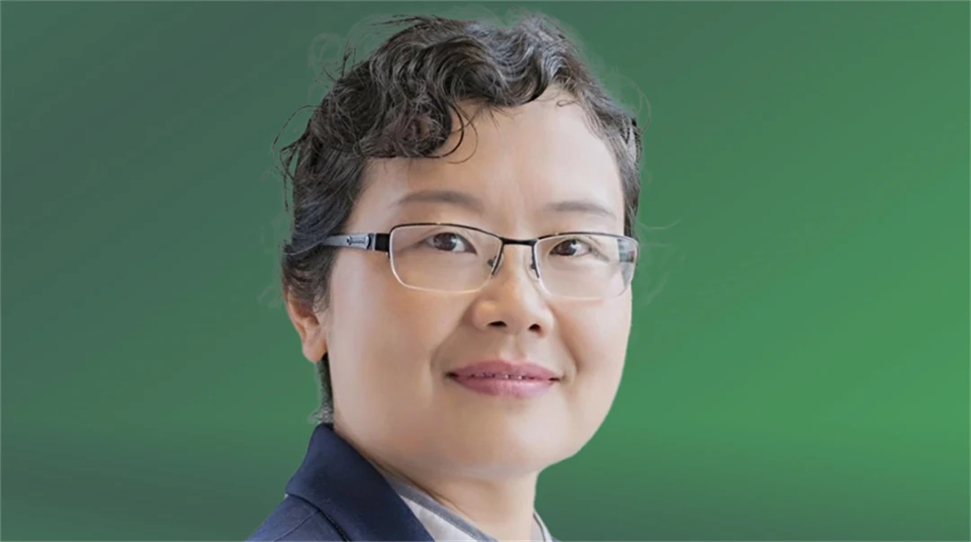 A woman with glasses looks into the camera.