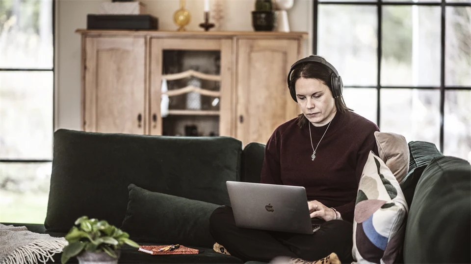 A woman is sitting in a sofa with a computer in her lap.