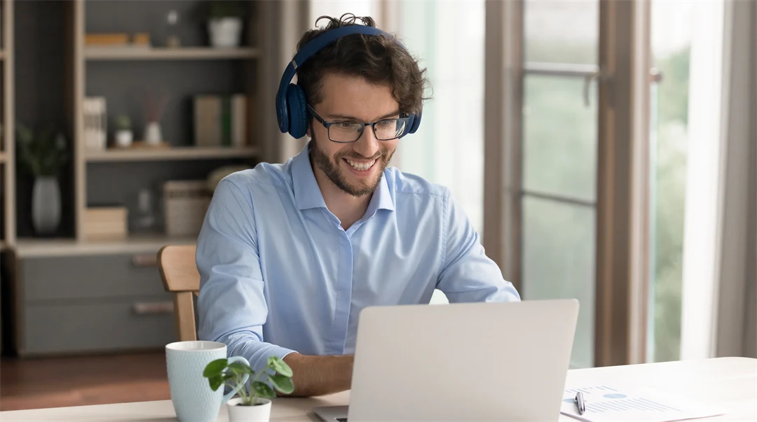 En ung man med hörlurar jobbar på en laptop