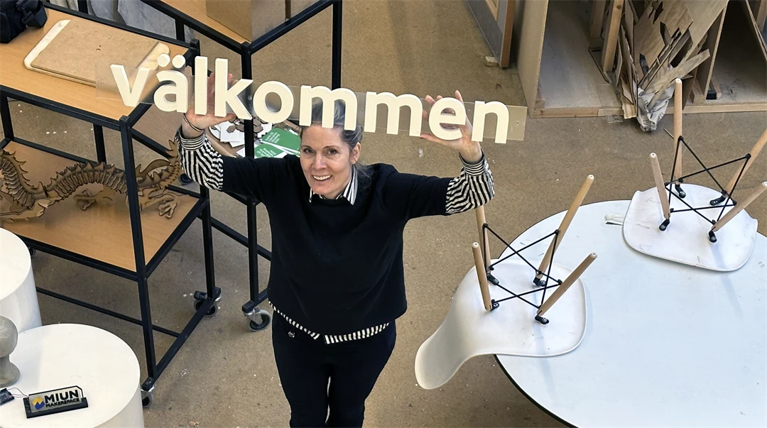 En kvinna håller en skult som det står välkommen på