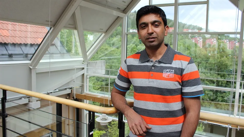 A man in a striped sweater poses in front of the camera.