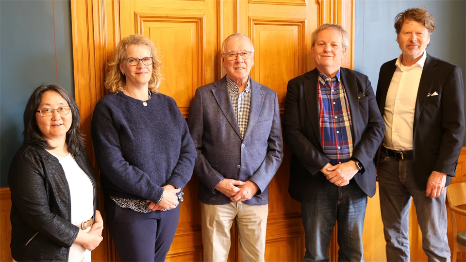 Två kvinnor och tre män uppradade framför en dörr