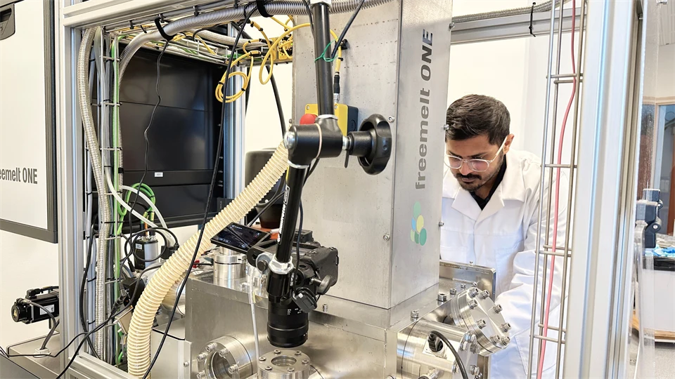 A man in a white coat working with a machine in a lab environment