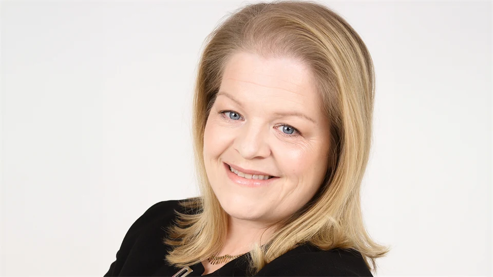 Kvinna med axellångt blont hår och svart kavaj i en porträttbild.