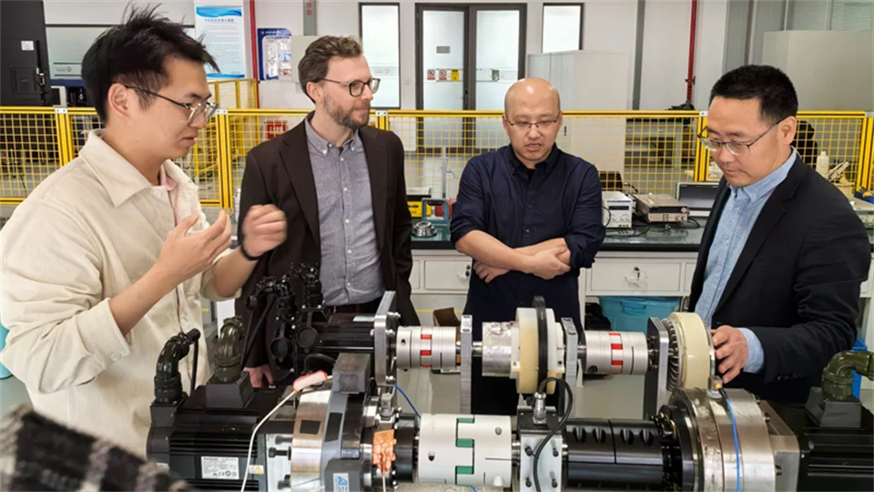 Fyra män står tillsammans vid utrustning i ett laboratorium där man forskar om kullager.