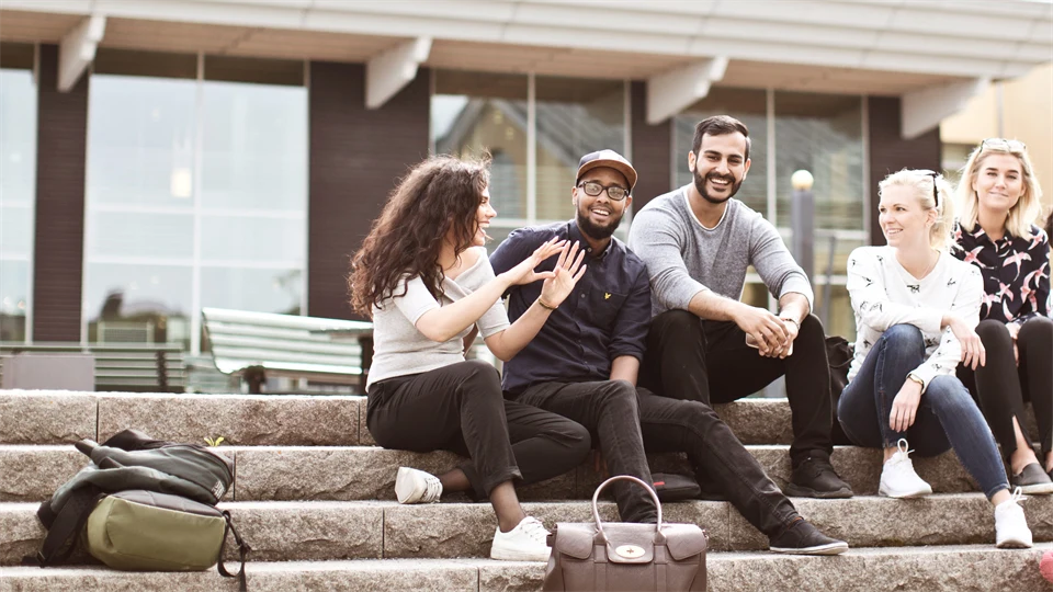 En grupp studenter sitter på en stentrappa, campus Östersund