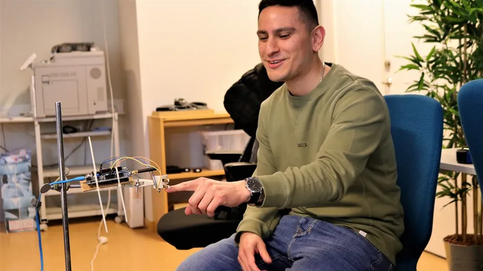 En man sitter ner och pekar på en lasersensor