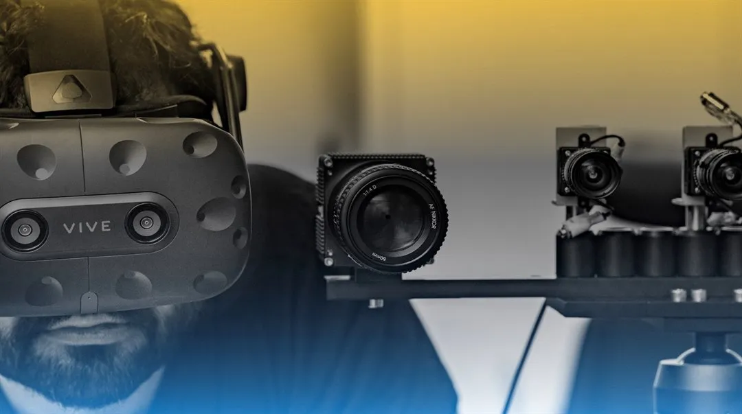 A man with a VR headset on standing next to a set up of smaller cameras.