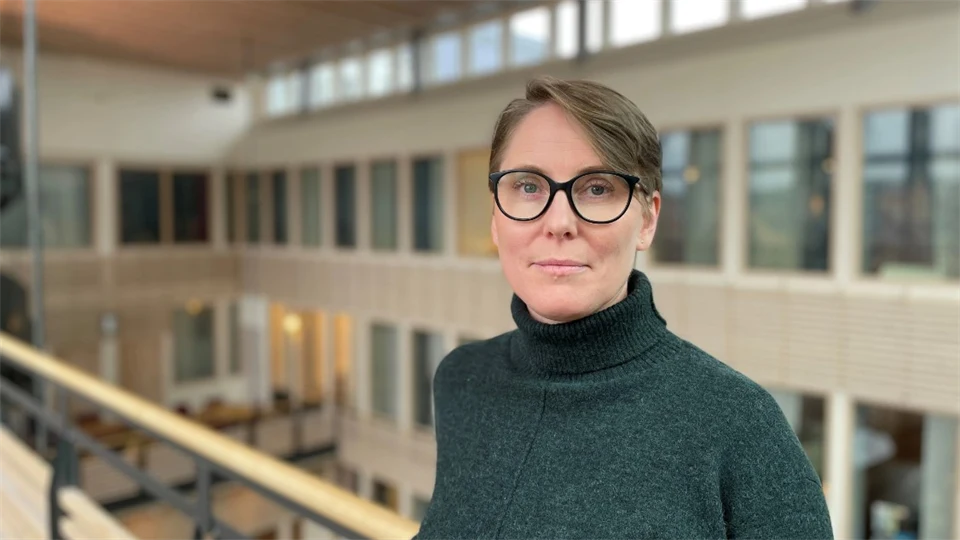 Porträttfoto av en kvinna med brunt hår och svarta glasögon
