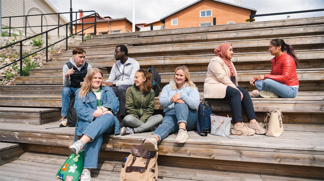 Seven students sitting on a staircase.
