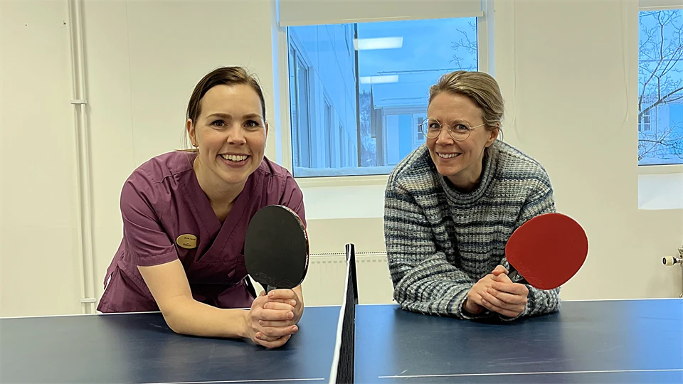 Två kvinnor står lutade mot ett pingisbord