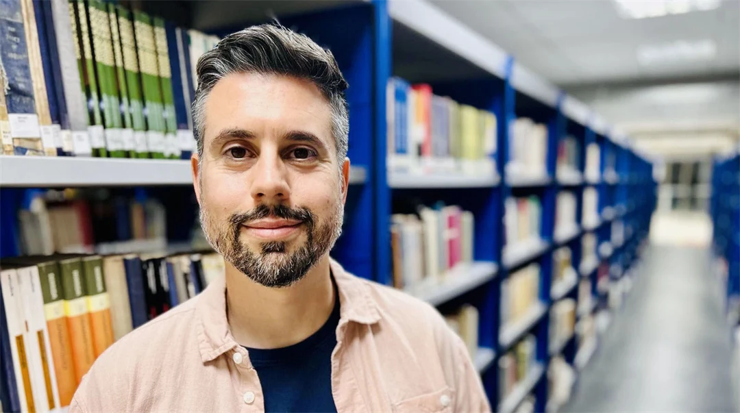 A man stands in a library with many books.
