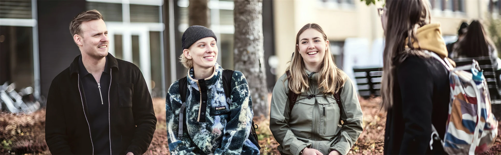 Fyra studenter sitter utomhus på campus i Östersund, de ser glada ut glada och pratar med varandra 