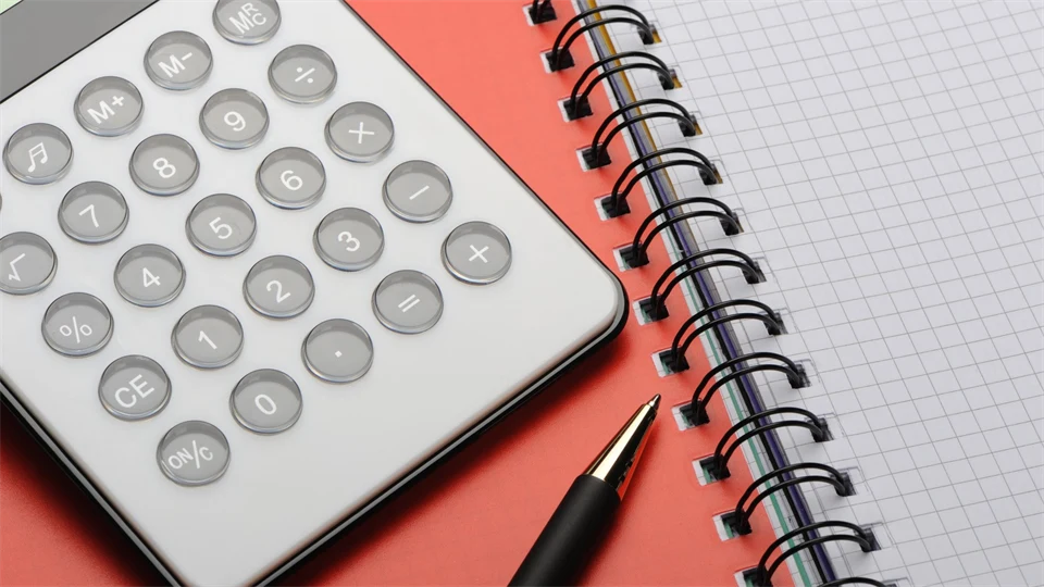 En miniräknare och en penna ligger på ett skrivblock.