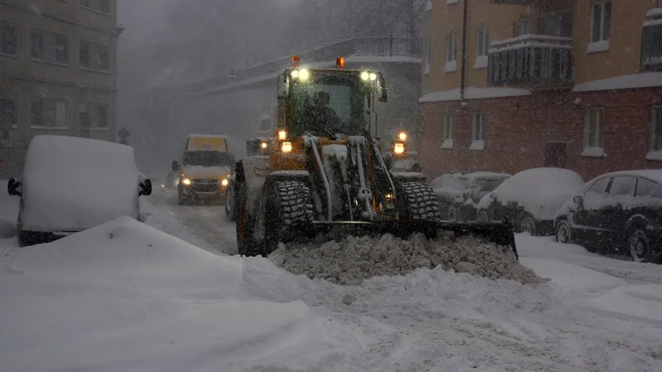 Traktor som skottar undan snö på gata.