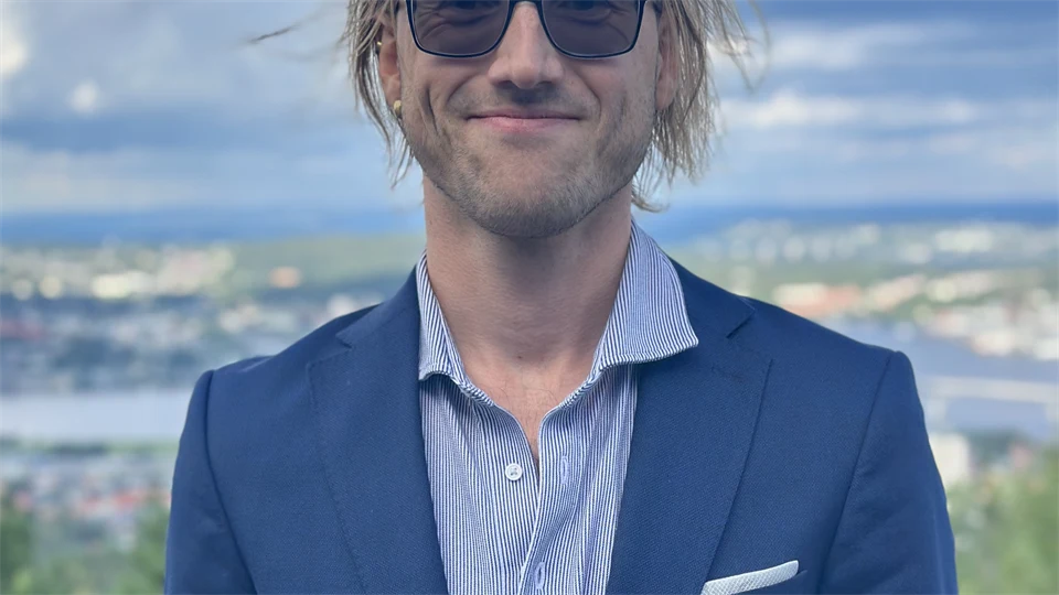 Portrait photo of a man with a blue jacket and dark glasses