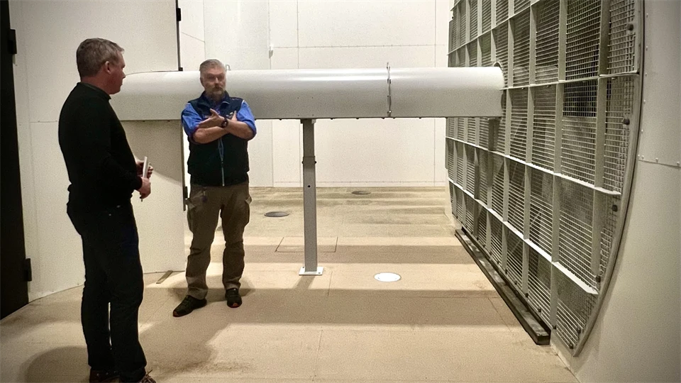 Två män står vid en stor fläkt.