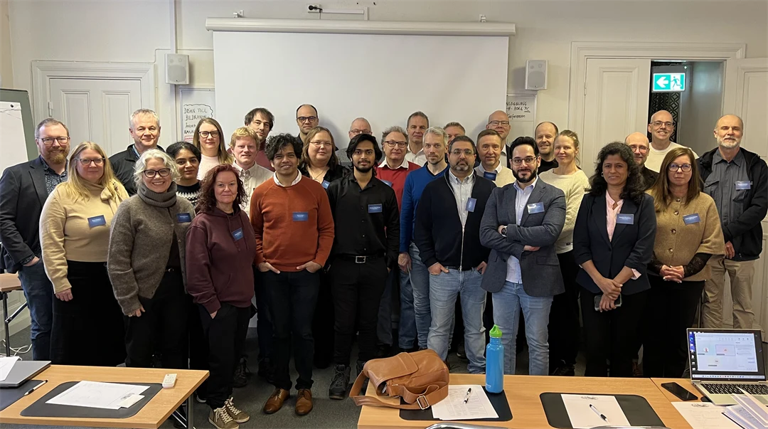 En grupp personer står tillsammans framför en whiteboardtavla.