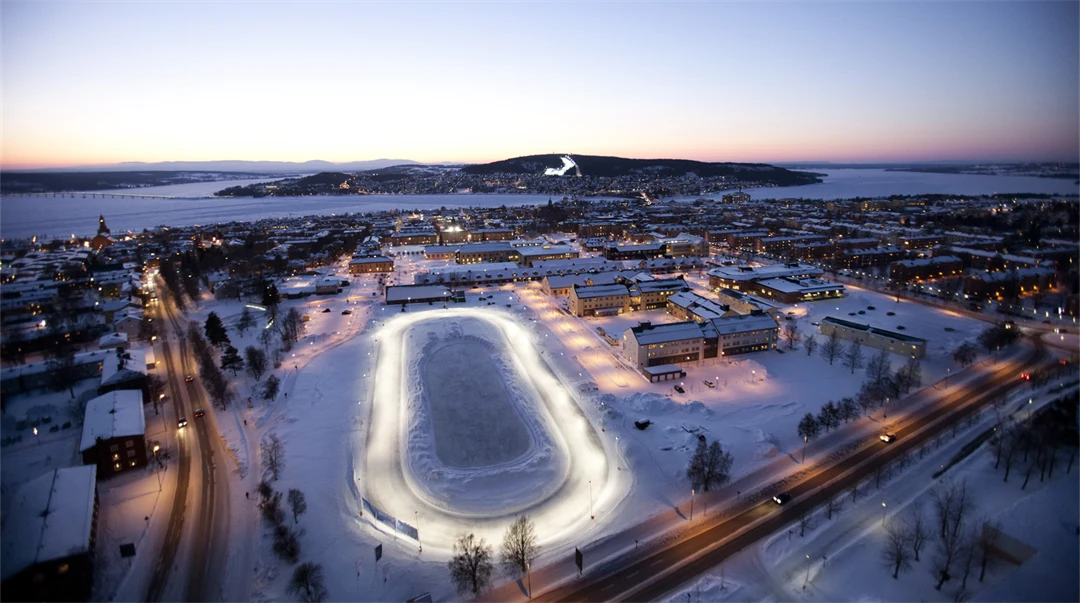 Fågelvy över en stadsbild med en sjö och fjäll i bakgrunden