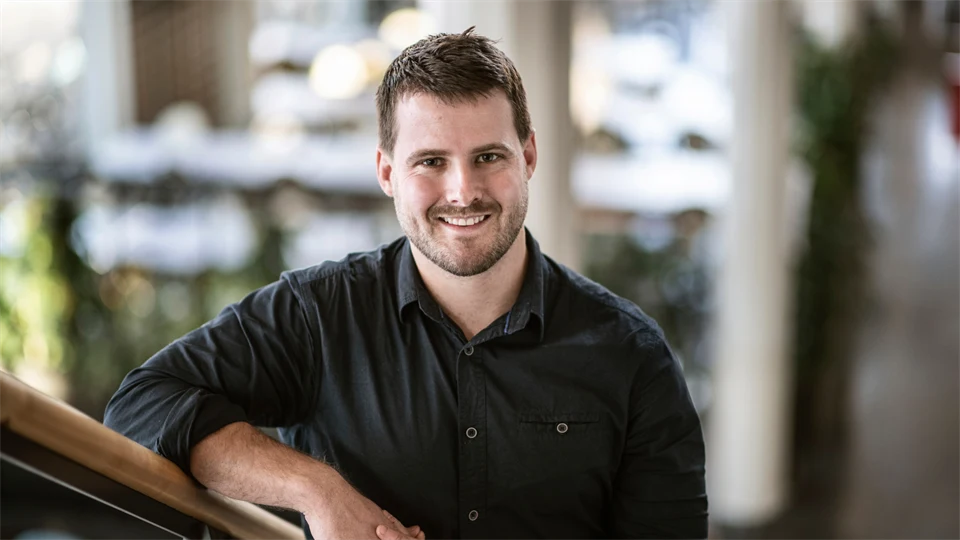 Daryl Aubry, phd student, standing in a flight of stairs on Campus Östersund. He looks happy.