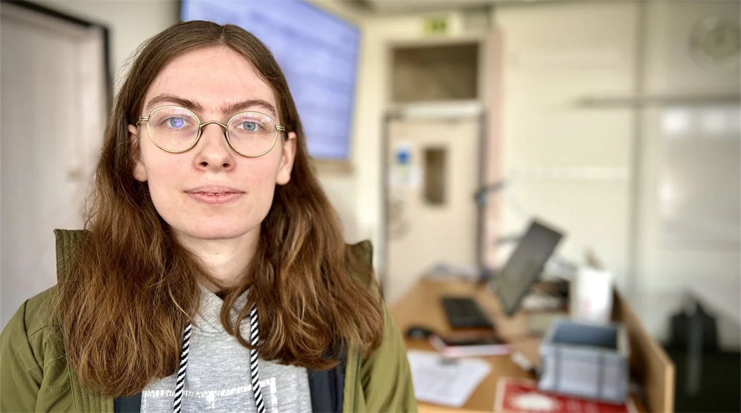 A woman with dark long hair is looking at the camera.