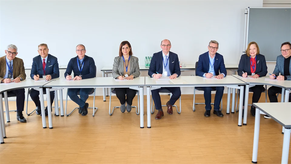 8 people in suits sitting by a table in a half circle