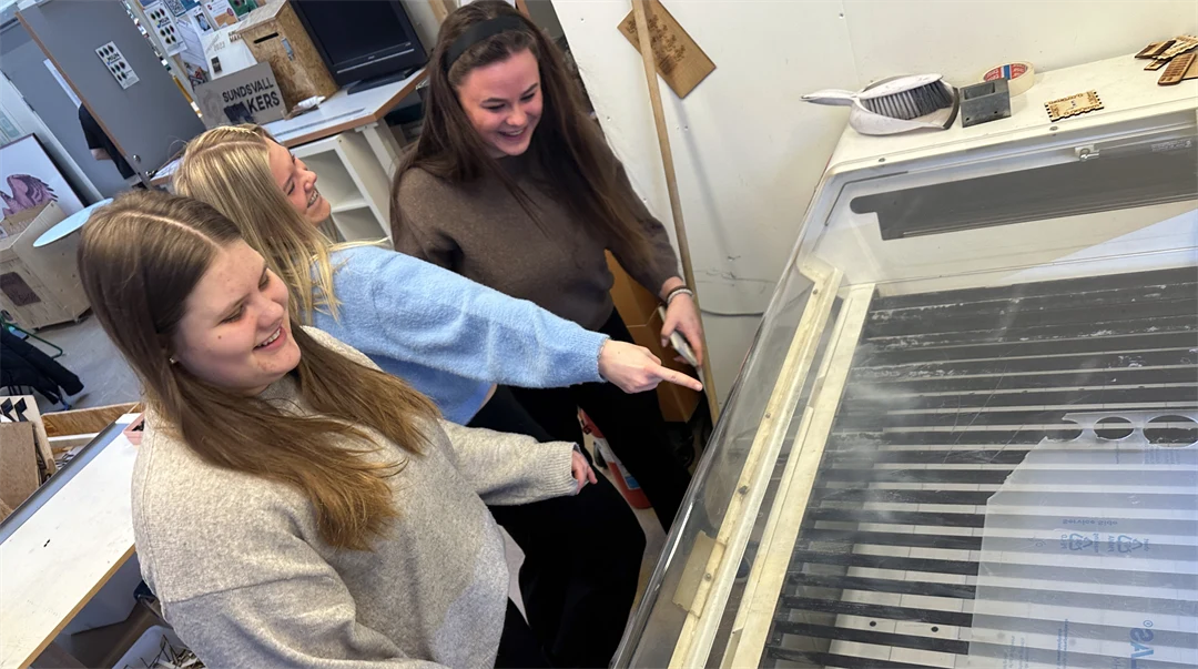 Tre kvinnor tittar på en maskin