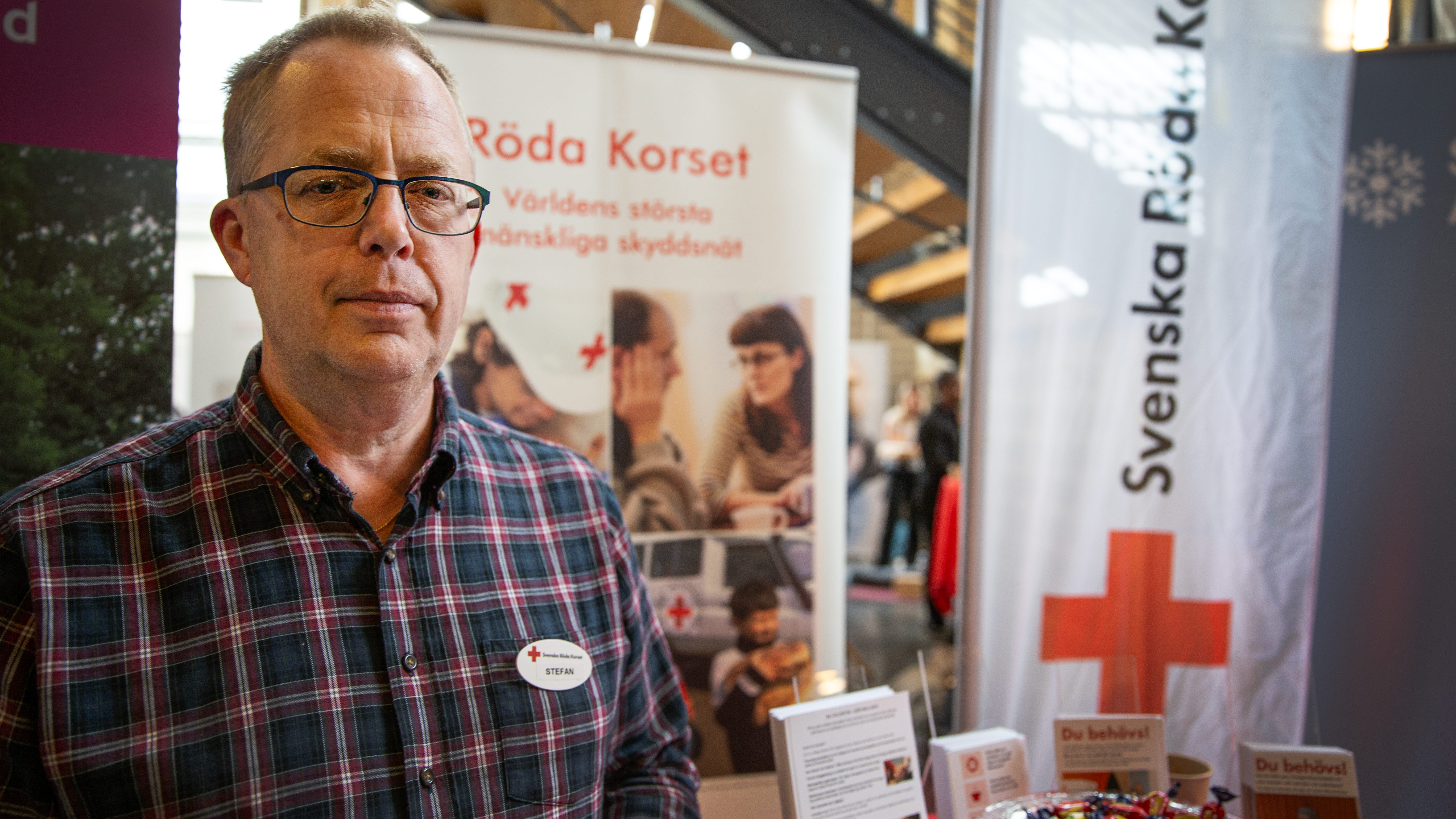 En man i rutig skjorta står framför ett mässbord.