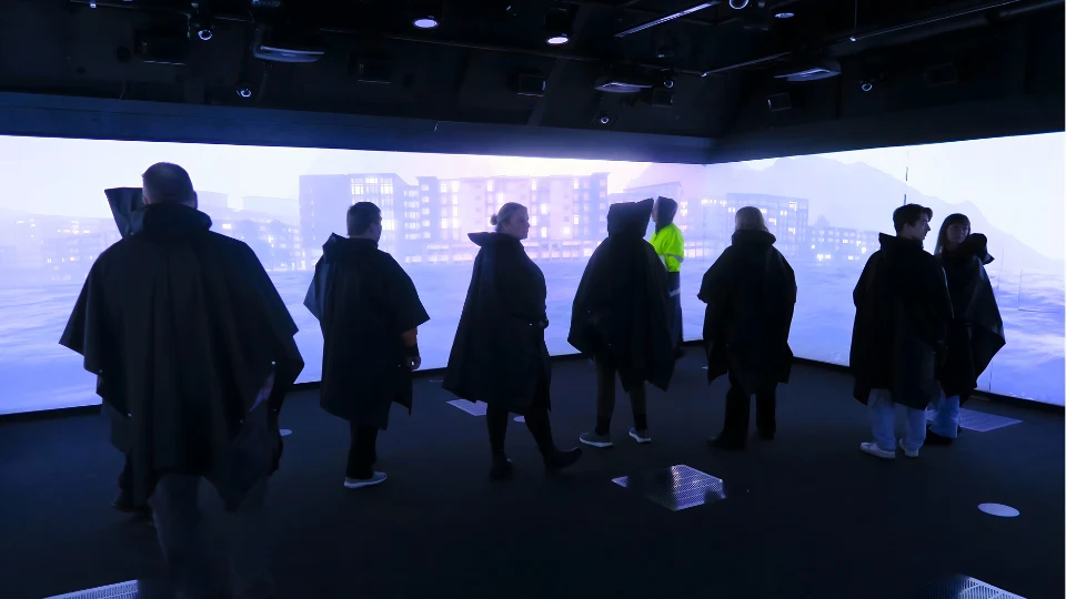 Sju workshopdeltagare står i RCR labbet framför stora bildskärmar