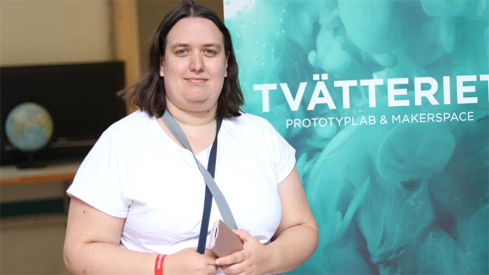 Kvinna i vit t-shirt står framför en blå rollup med texten "TVÄTTERIET"