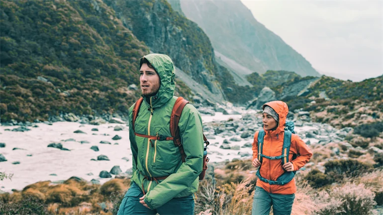 Hikers on trek with backpacks living healthy active lifestyle. Hiker girl walking on hike in mountain nature landscape.