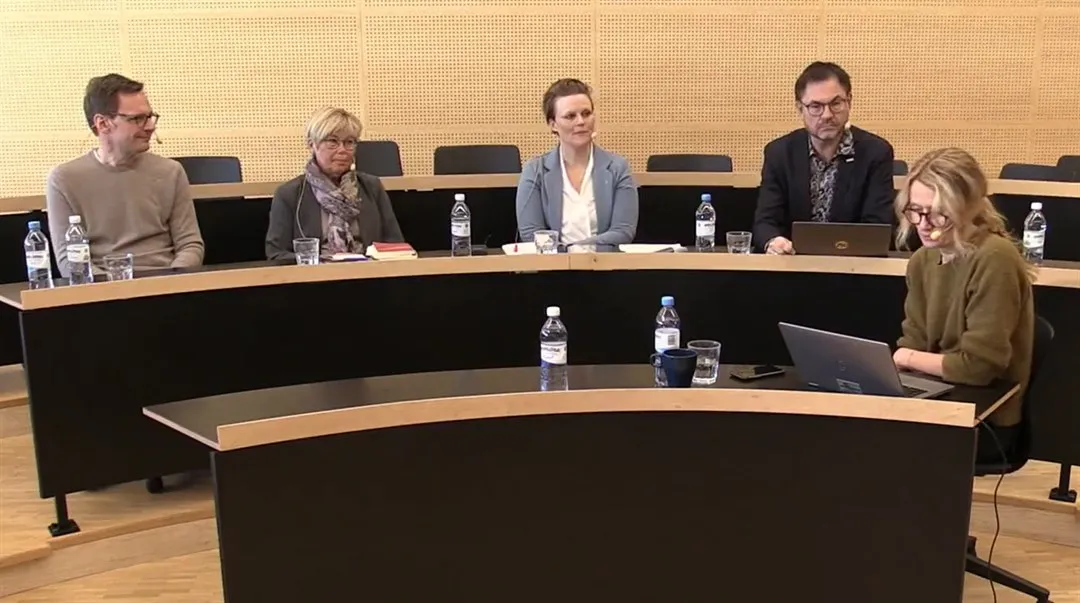 Fem personer sitter i en föreläsningssal på två olika rader.