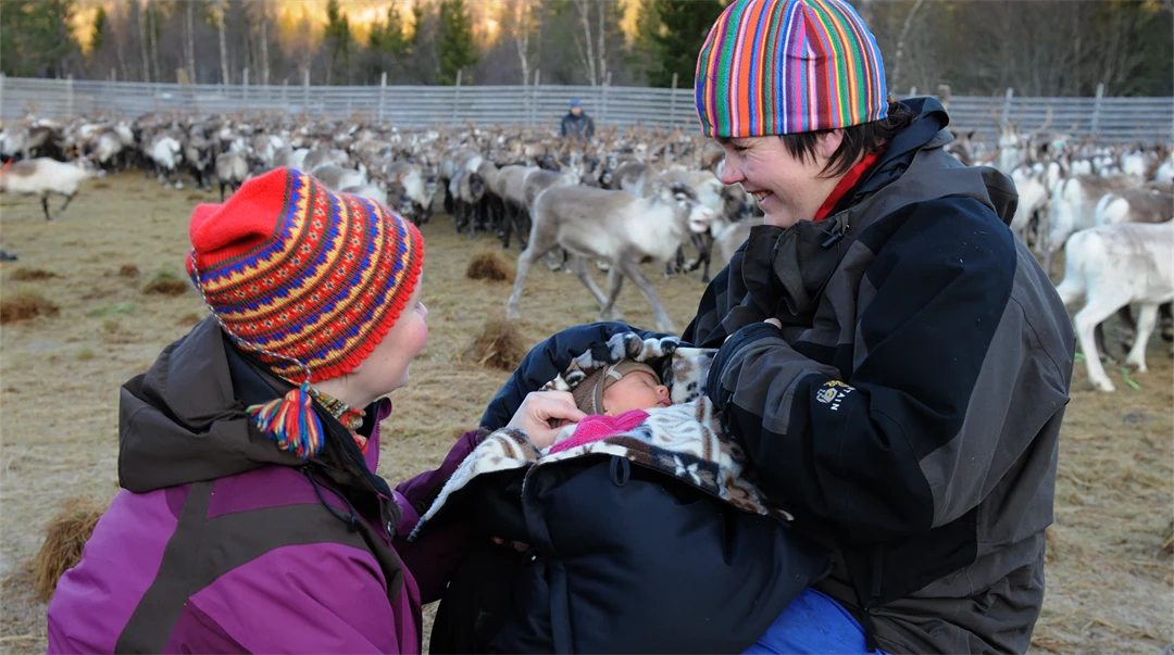 Kvinna med två barn i ett rengärde.