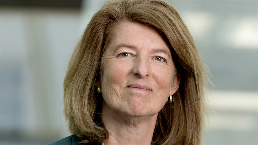 Porträttbild på kvinna med kavaj som står med armarna i kors. 