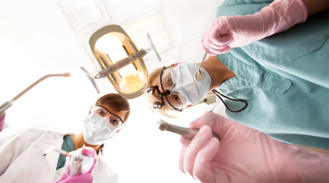 Två tandläkare med instrument tittar in i kameran