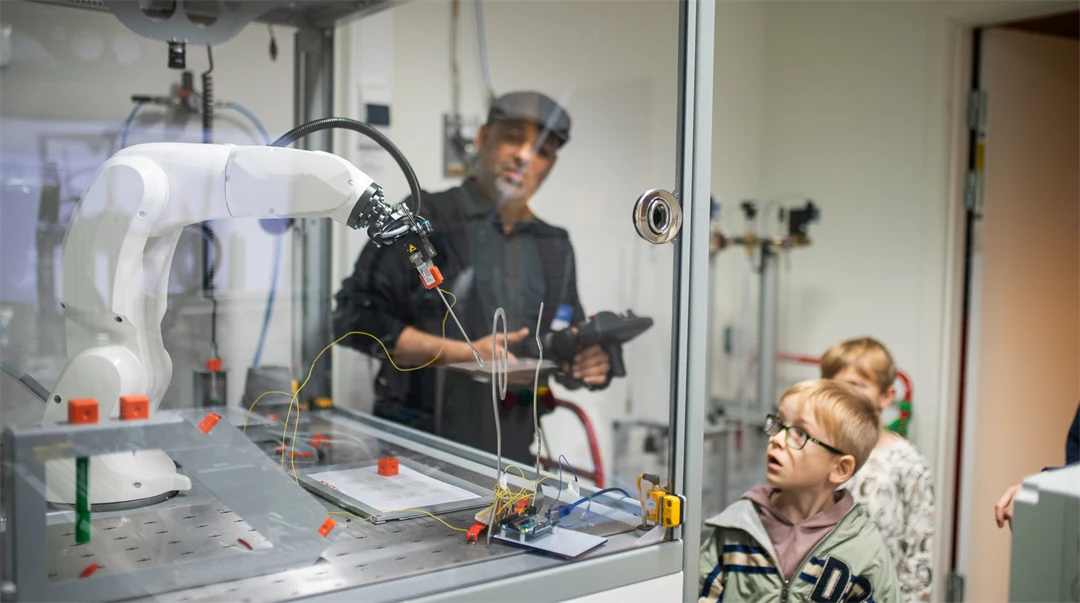 Kids looking at a robot arm in the lab.
