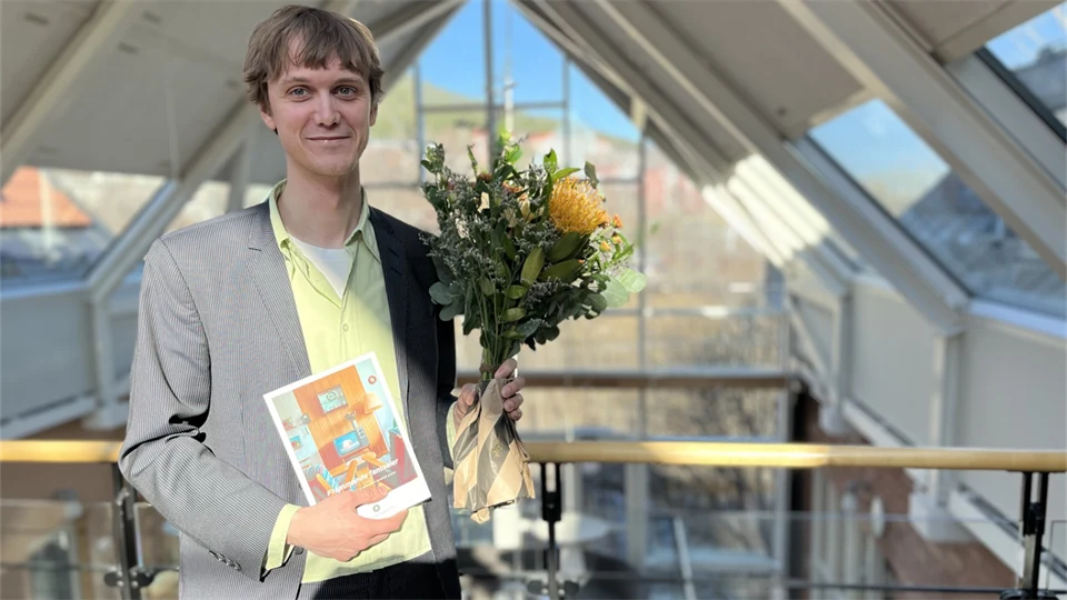 Man med en blomma i ena handen och ett diplom i den andra. 