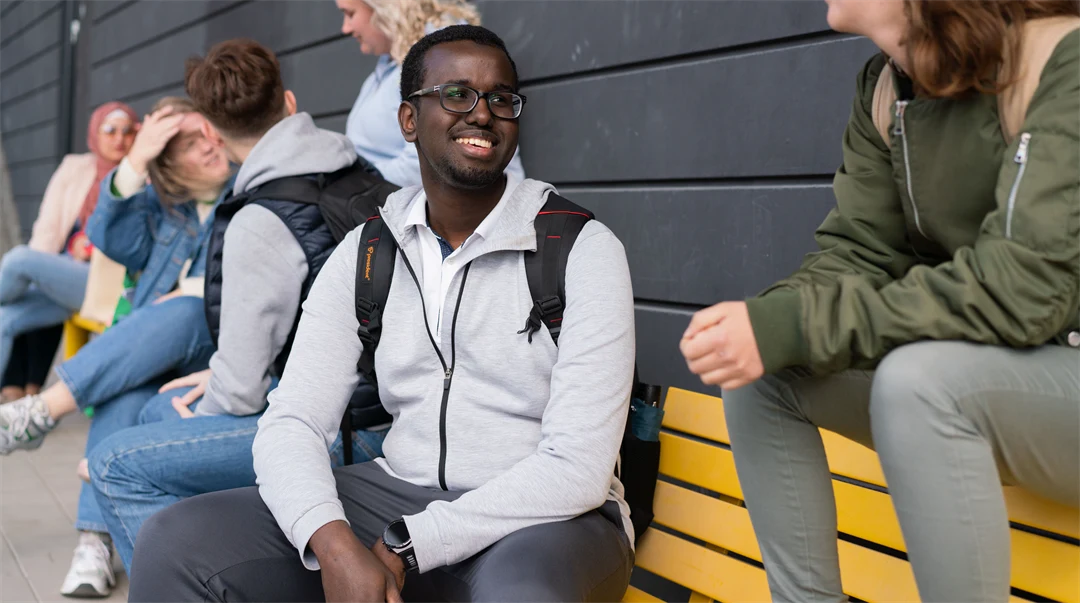 Studenter som sitter på en gul bänk. 