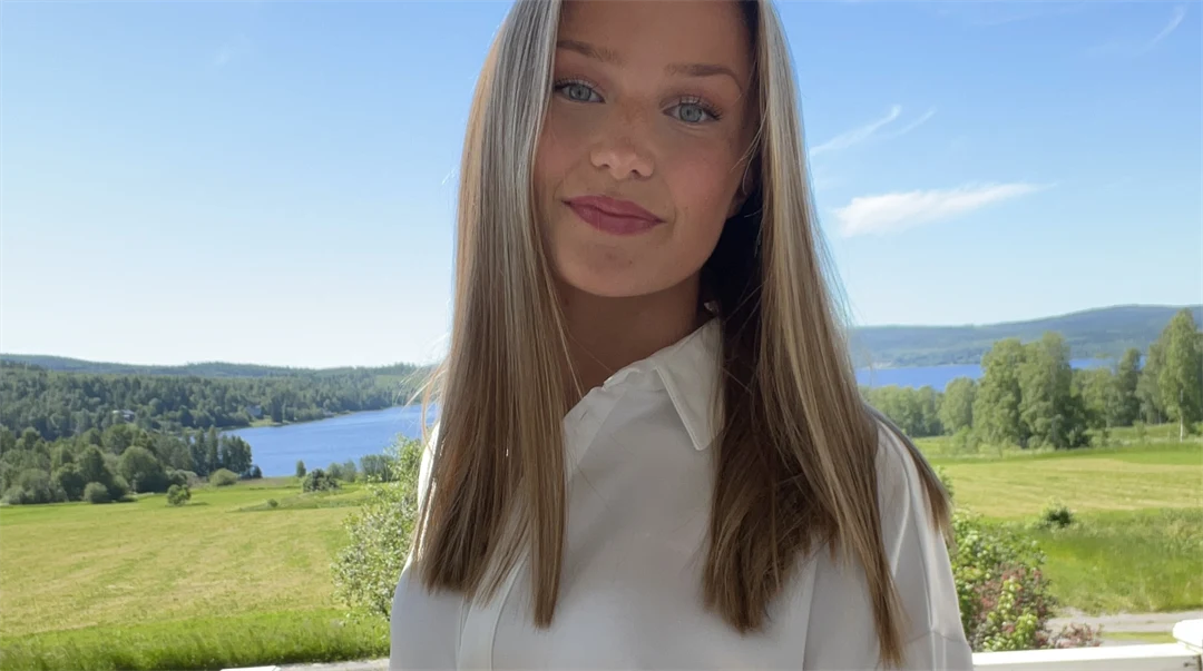 En kvinna med vit skjorta framför ett gräsfält