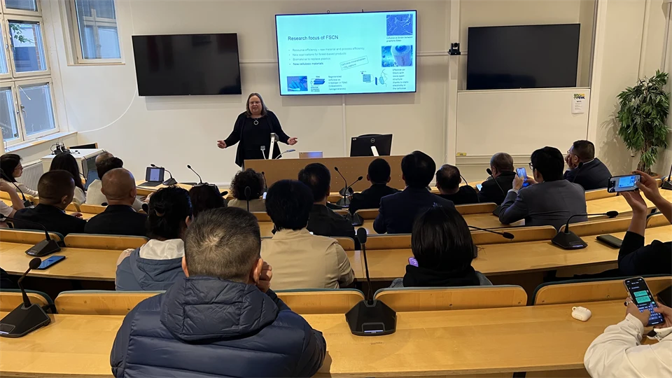 A group of people are sitting in a lecture hall, and one person stands at the front facing those listening.