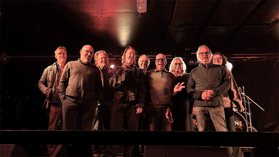 En grupp människor samlade på en scen i en mörk klubblokal