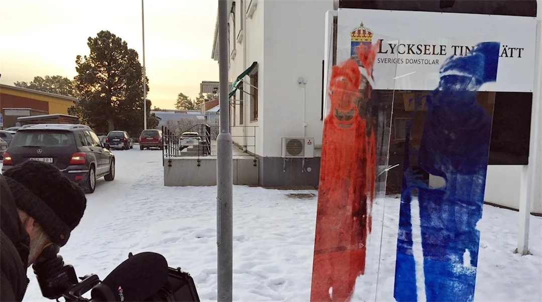 Fotograf tar bild av glas med en röd och en blå same målade på, utanför Lycksele Tingsrätt