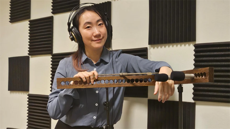 Woman in a blue shirt, with headphones on her head, leans over an array of microphones.