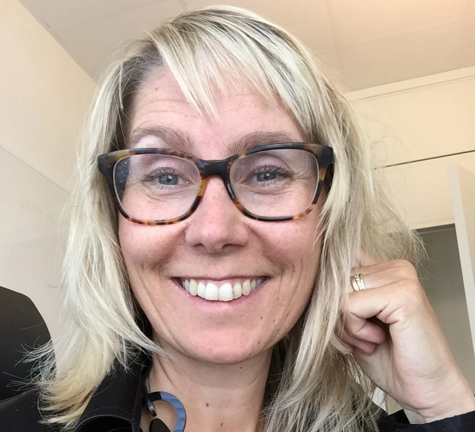 En kvinna ler och tittar in i kameran