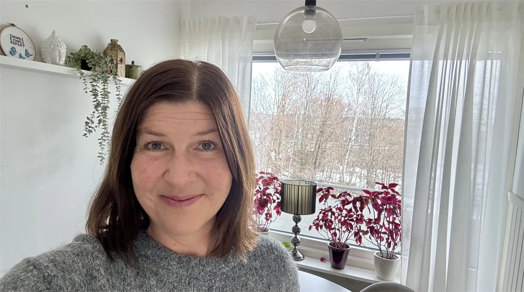 Kvinna med kort, mörkt hår som ler mot kameran