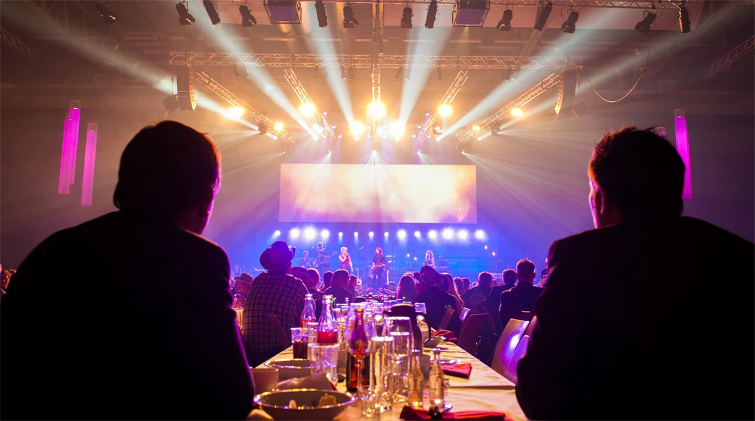 Två personer sitter vid ett middagsbord och tittar på underhållning