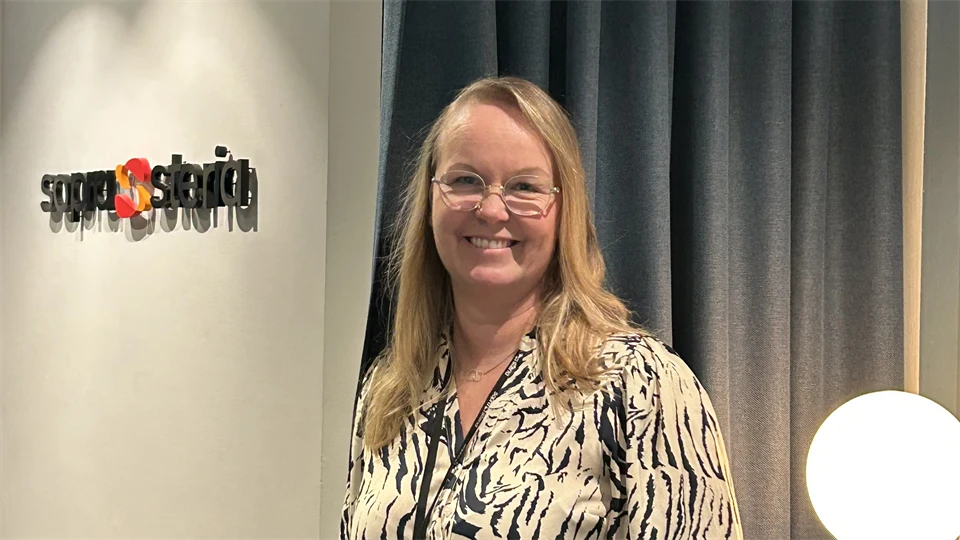 En kvinna tittar in i kameran och ler. 