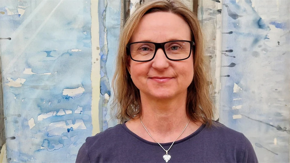 En kvinna tittar in i kameran och ler. 